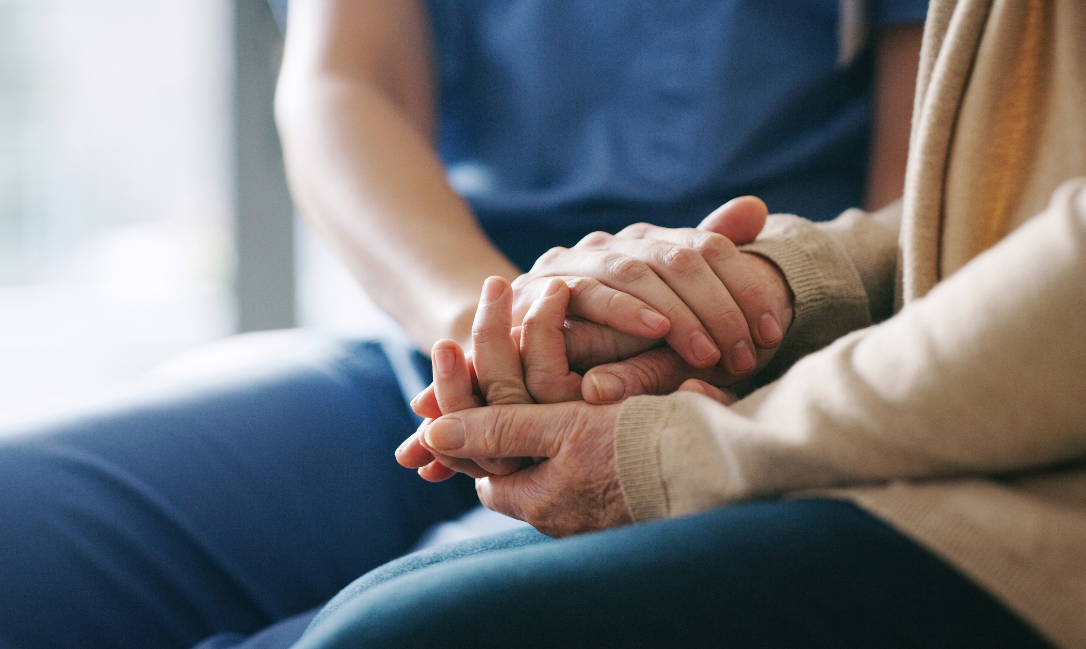 nurse holding hands of olders women